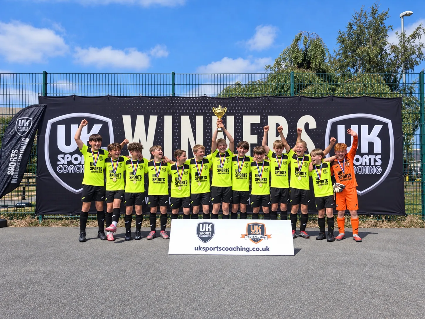 Youth football team lined up with medals and trophy in front of the UK Sports winners backdrop